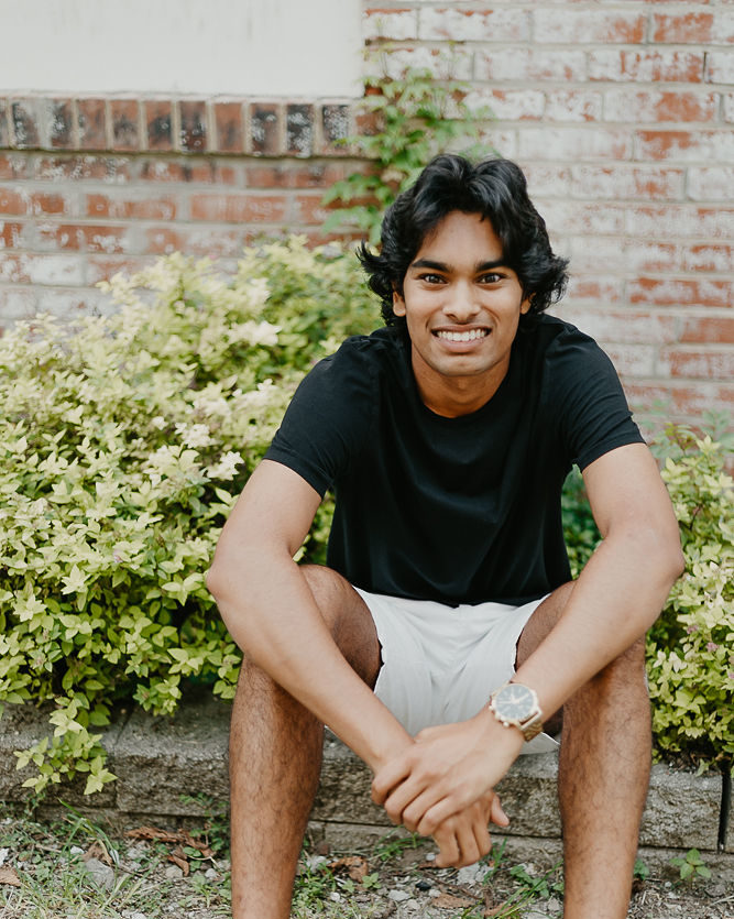 smiling man sitting on curb with elbows on his knees