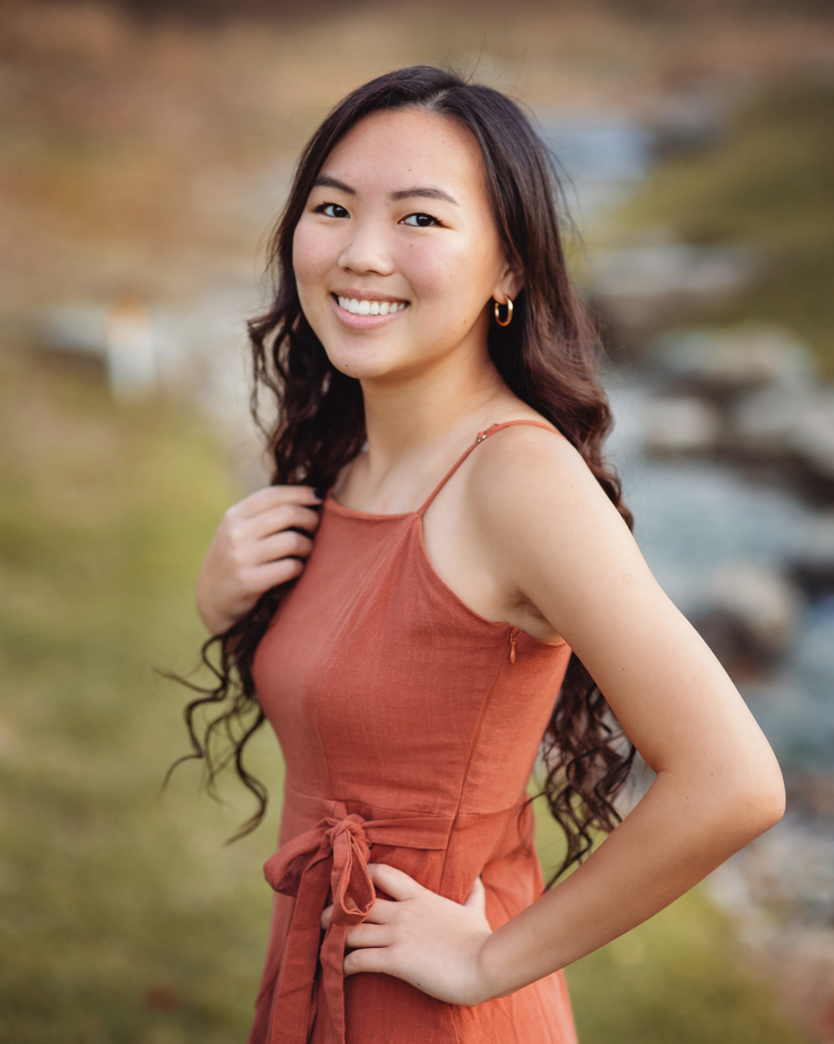 smiing girl in terracotta dress with one hand on hips