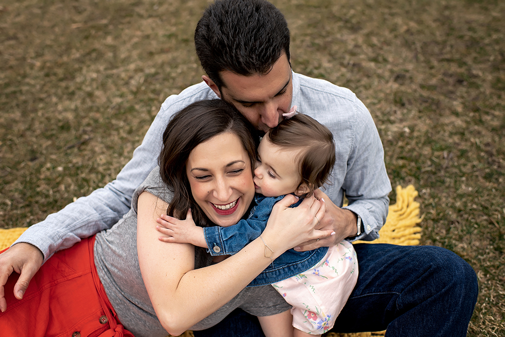 man holding smiling woman and kissing baby