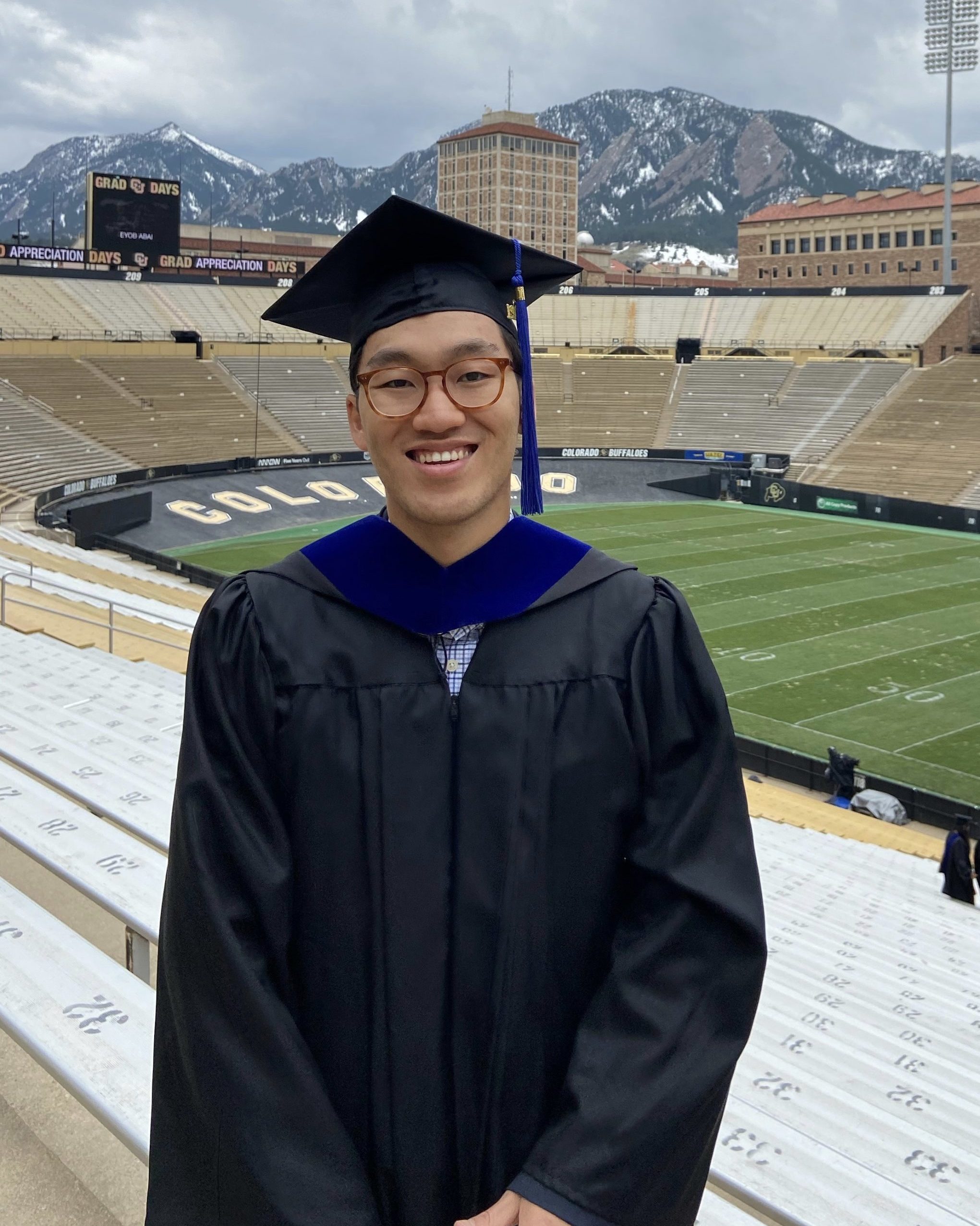 smiling man wearing glasses wearing black graduation cap and gown