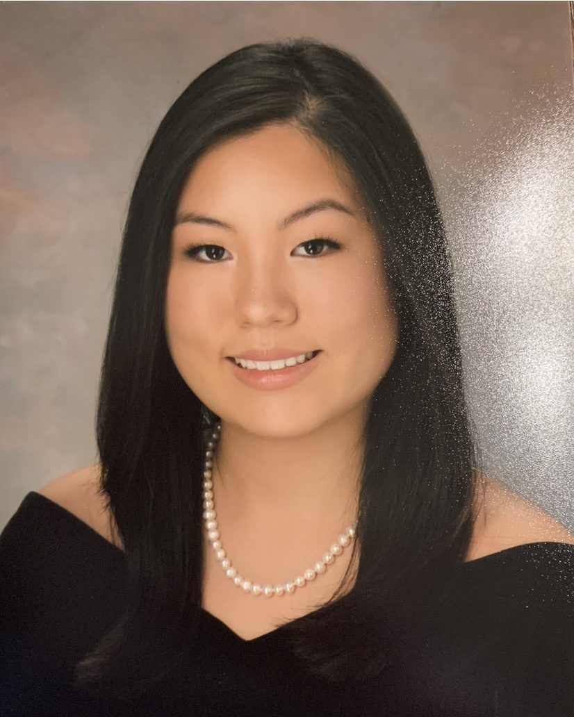 school photo of smiling girl wearing black off the shoulder top and pearl necklace