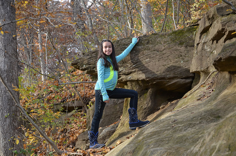 girl in blue jacket posing next to rock formation