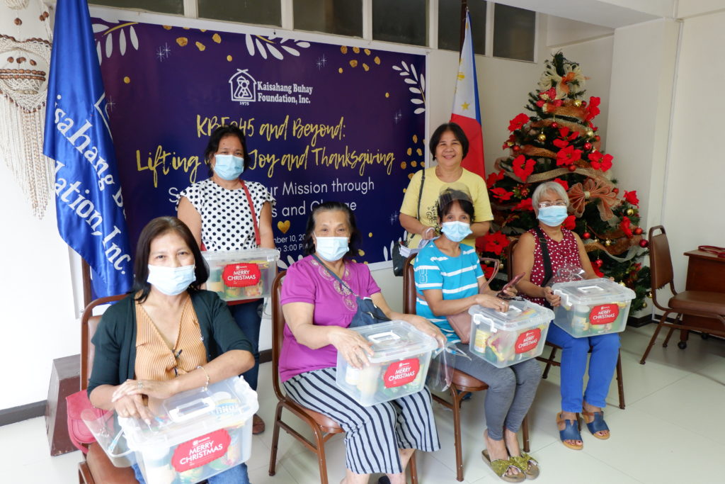 foster families smiling with boxes of supplies in front of Christmas decor