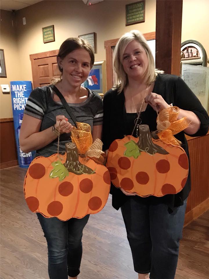 two woman holding handmade pumpkin signs