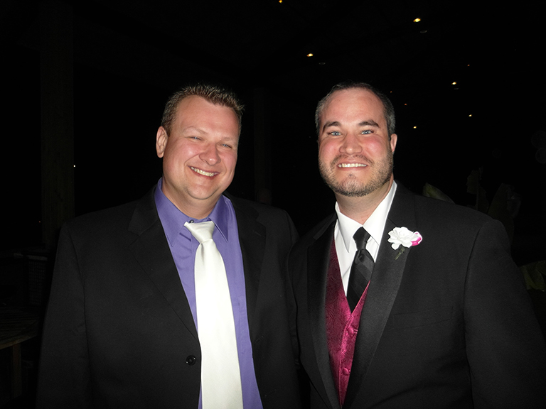 two men in formal suits smiling at camera