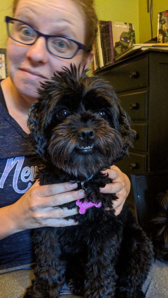 woman holding black curly haired dog