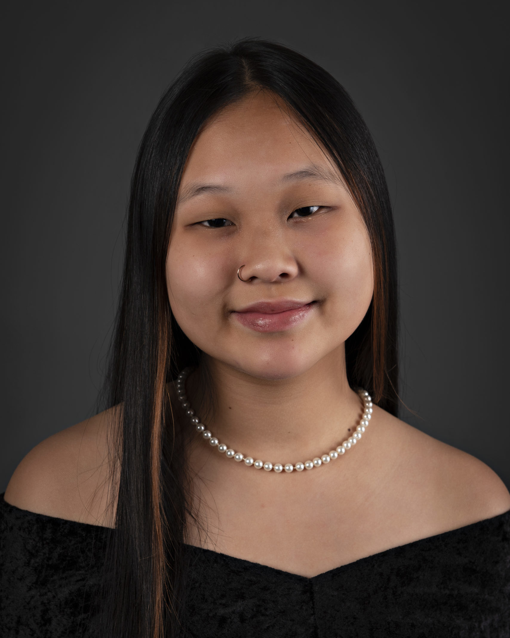 school photo of smiling girl wearing black off the shoulder top and pearl necklace