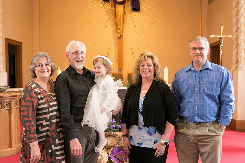 group of people with baby in baptism dress