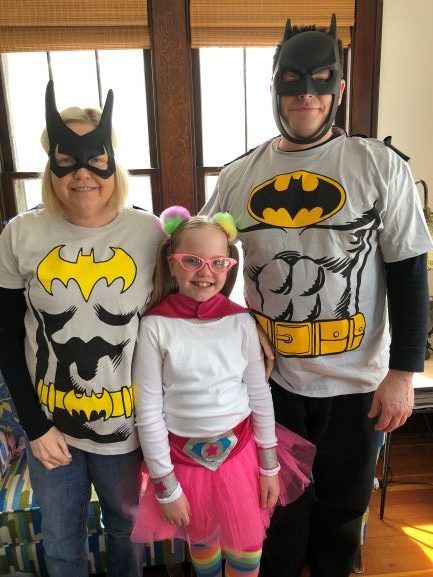 dad and mom in batman costumes with daughter in pink tutu