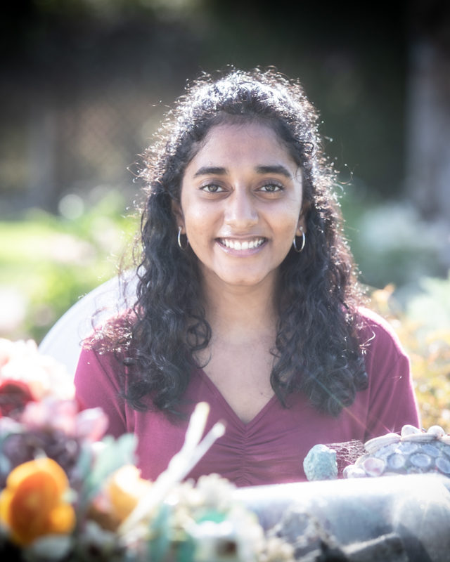 smiling girl with curly hair sitting in a garden