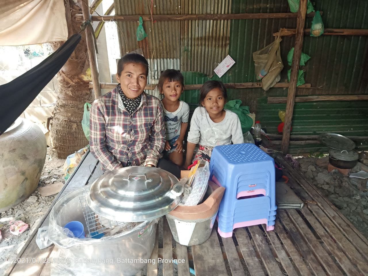 woman and two children smiling sitting by cooking supplies