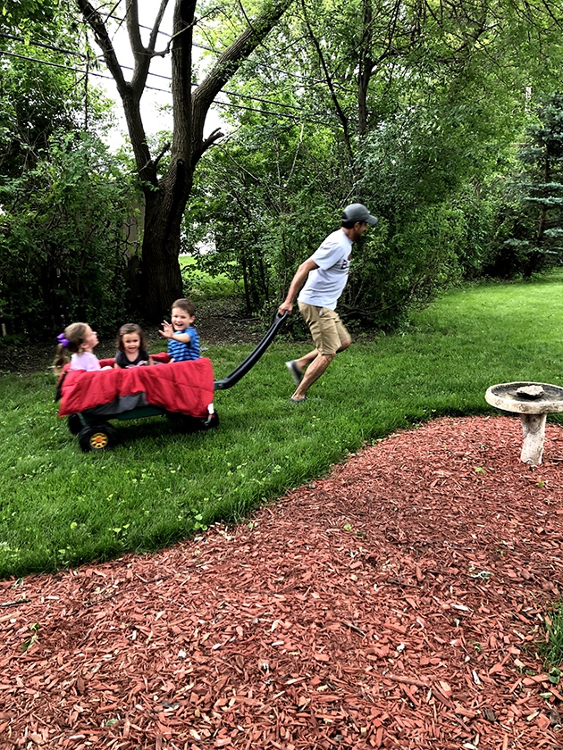 man pulling three laughing children in a wagon