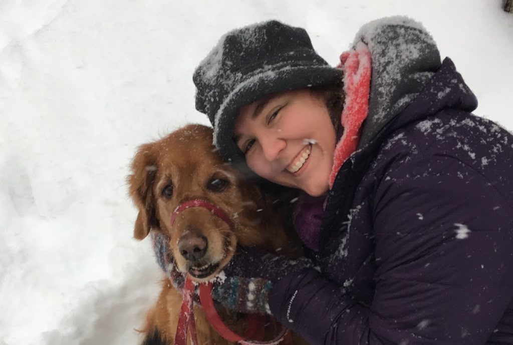 woman playing in snow with golden retriever