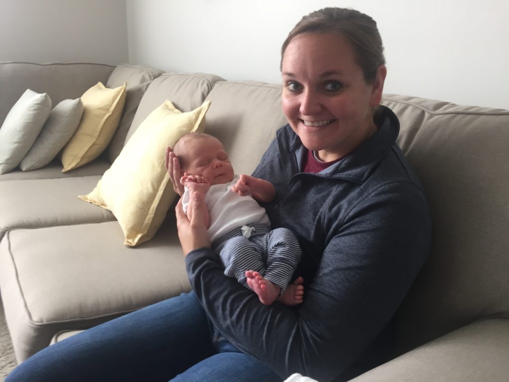 woman holding a newborn baby sitting on a couch