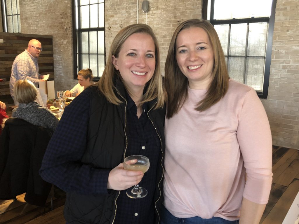two women smiling for a picture with drinks