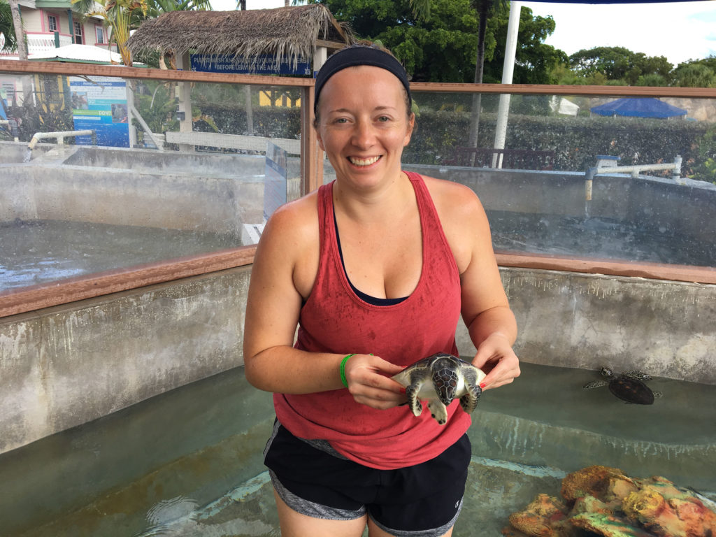 woman in red tank top holding a turtle