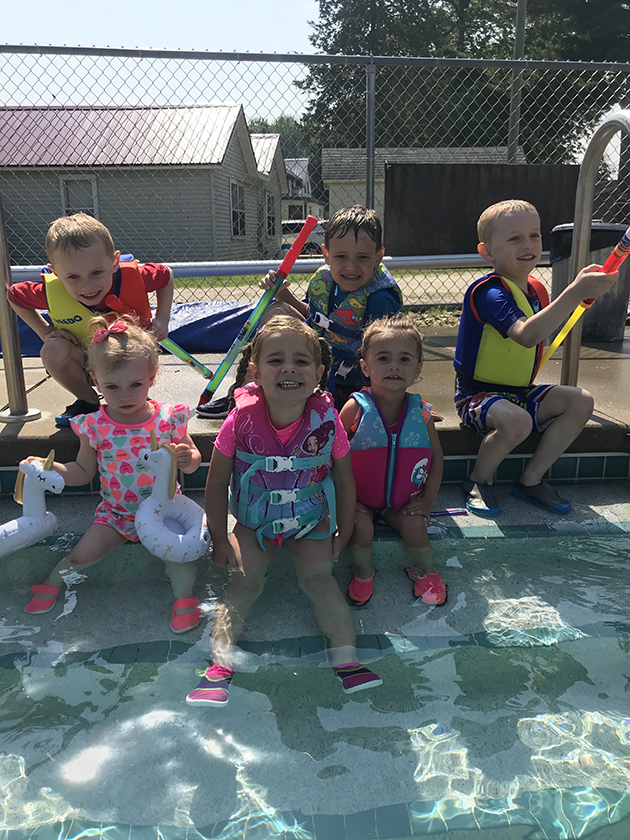 six children in colorful lifejackets in a swimming pool