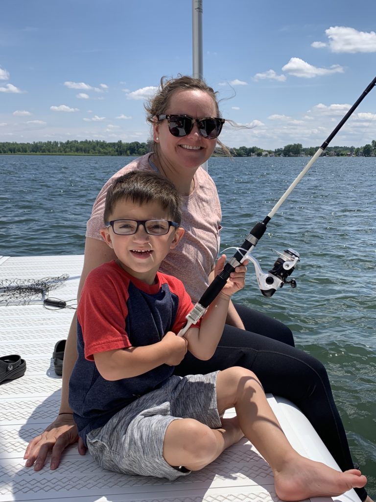 little boy holding fishing pole with woman smiling on boat