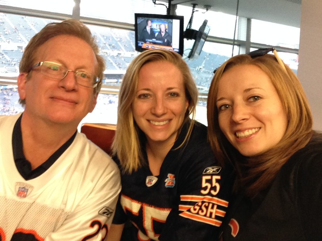 two women and one man smiling wearing football jerseys