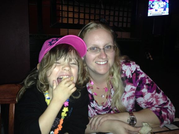 smiling blonde woman with laughing little girl in pink hat