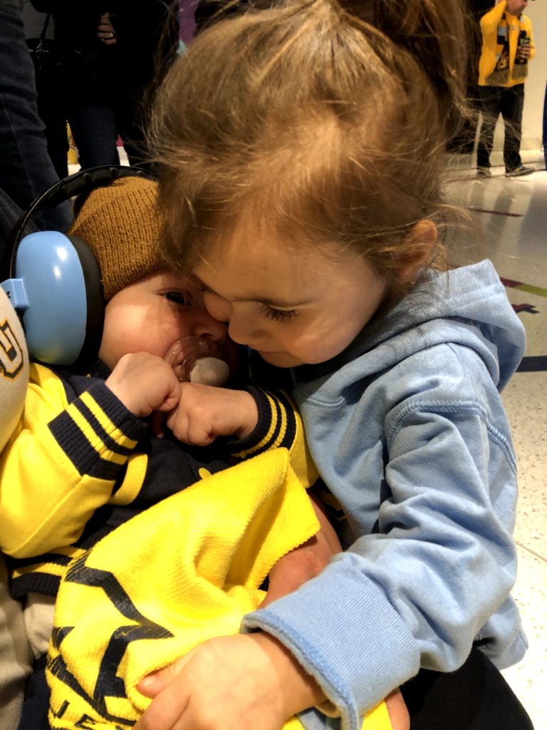 toddler girl giving a baby a hug