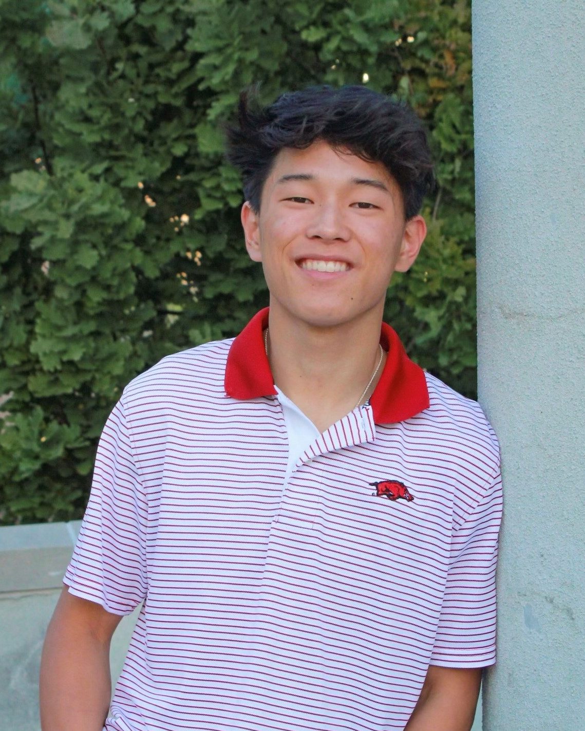 smiling man wearing red and white striped polo shirt