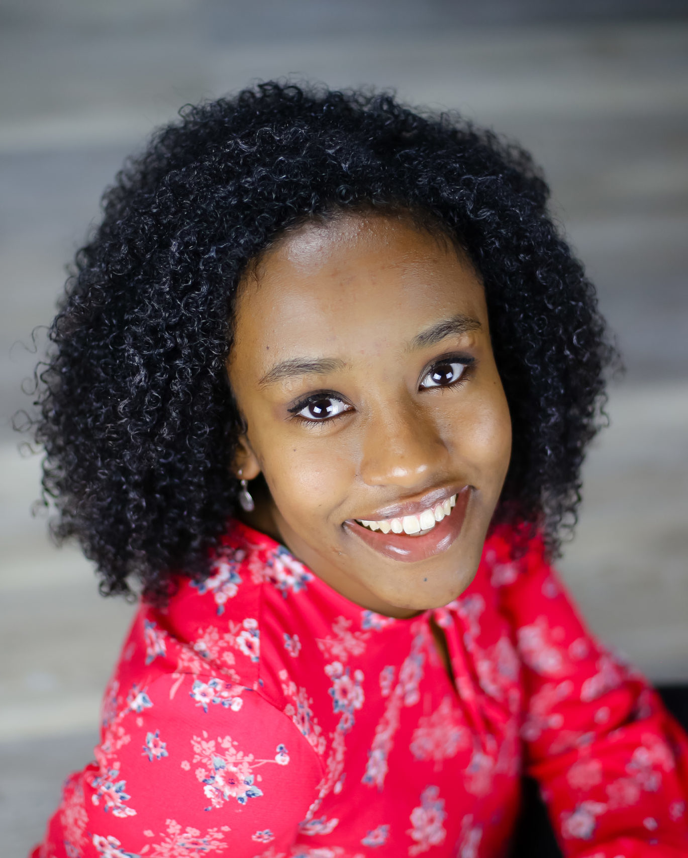 smiling girl with curly hair wearing red flowered top