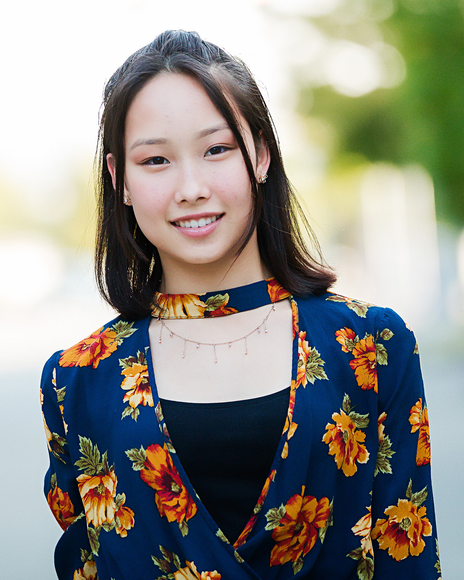 smiling girl with short hair wearing navy blue and orange floral top