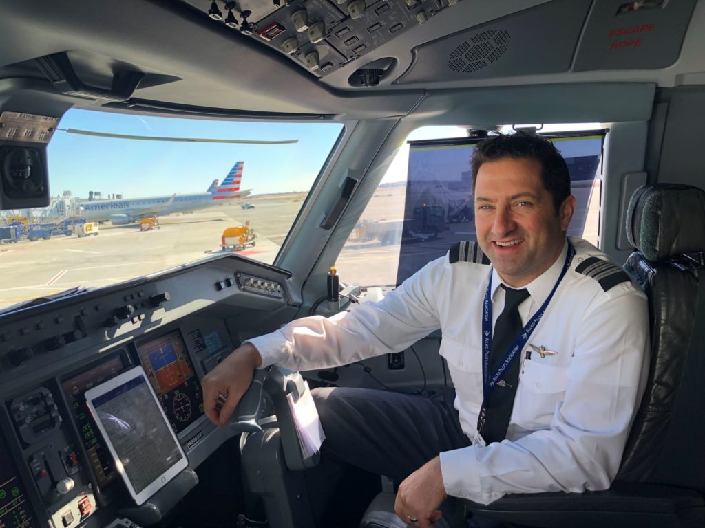man wearing pilot uniform in the cockpit of a plane