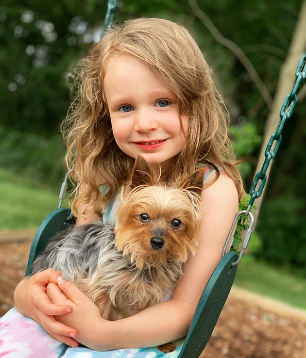 little girl sitting on swings holding yorkshire terrier