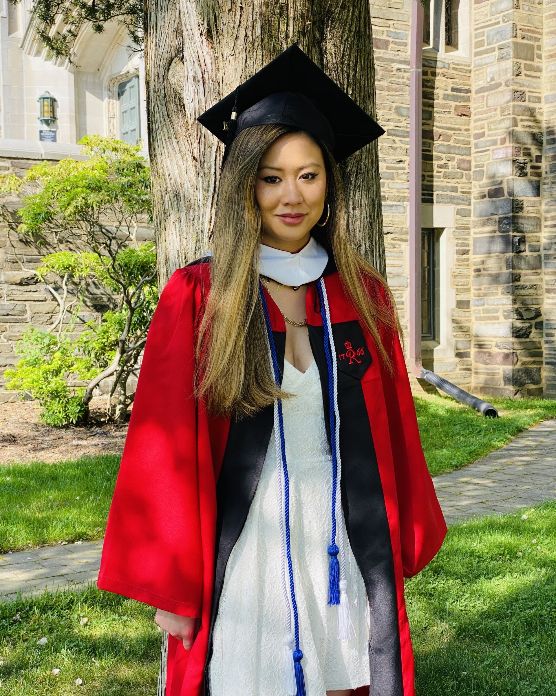 smiling girl wearing red graduation gown and black graduation cap