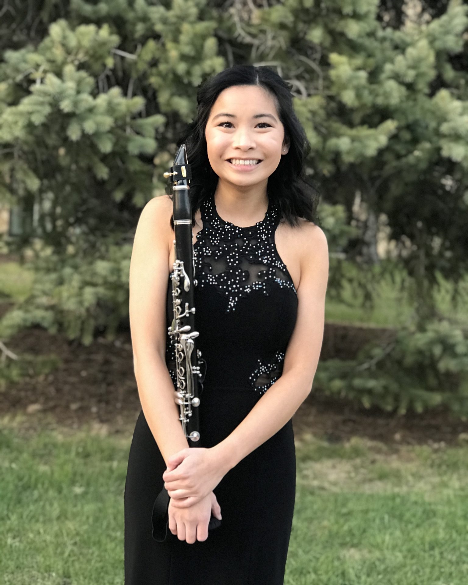 smiling girl wearing long black dress and holding clarinet