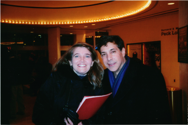 smiling woman holding red folder next to smiling man