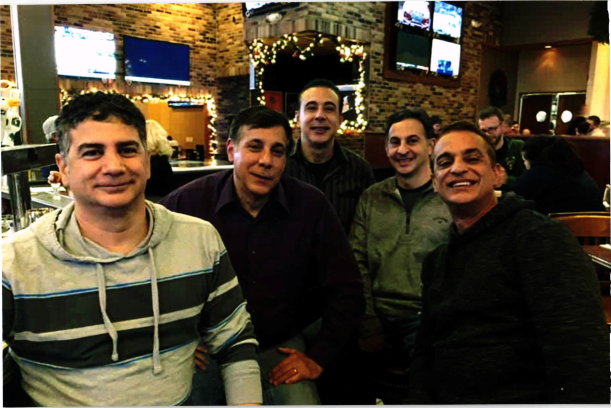 group of five smiling man at a restaurant