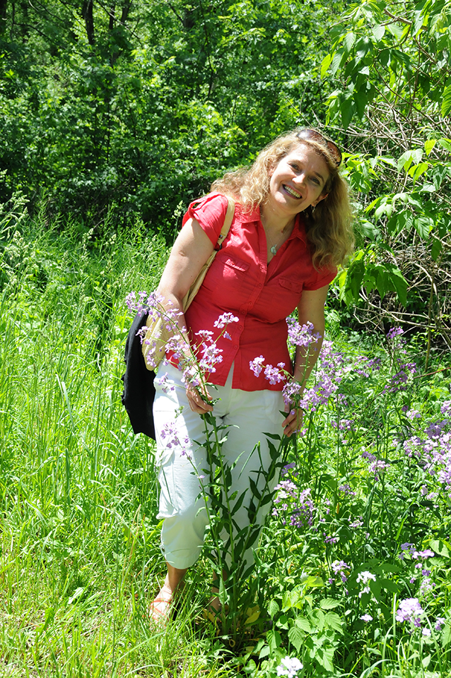 smiling woman in red blouse in field of pink flowers
