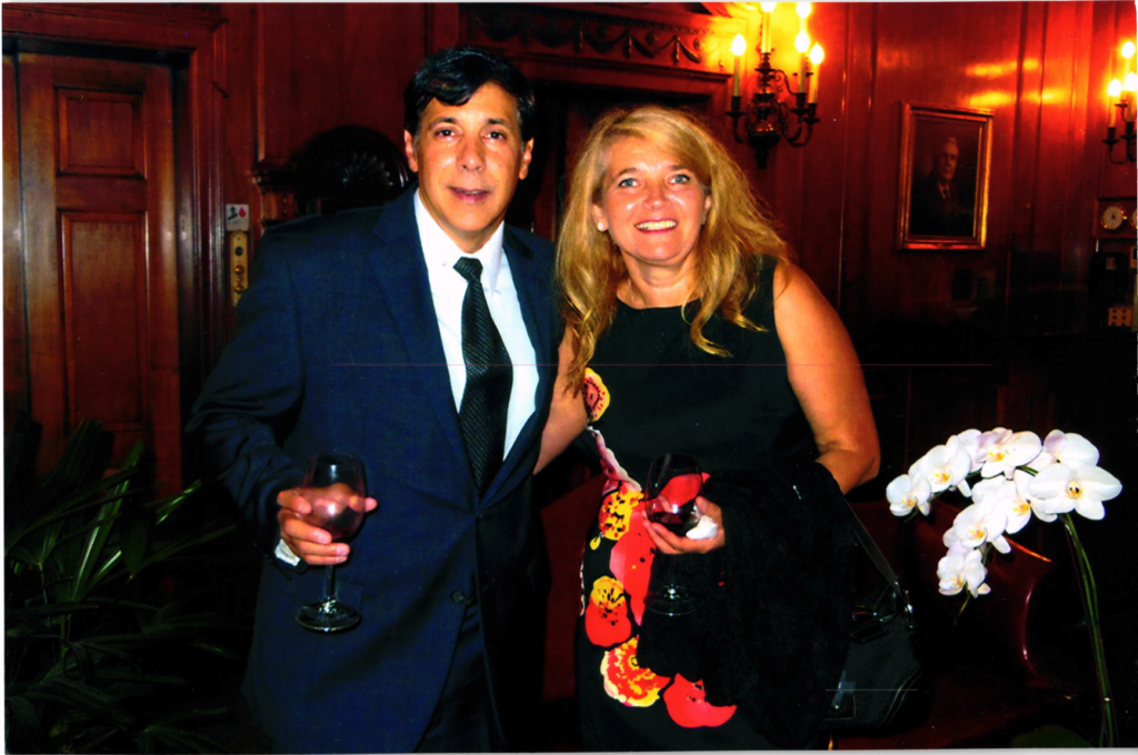 smiling man holding wine glass with arm around smiling blonde woman