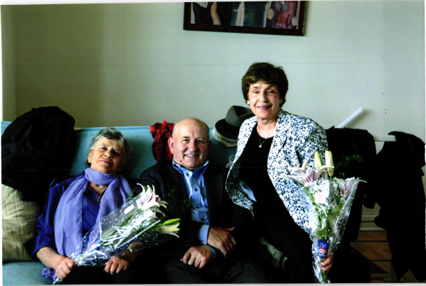 two women holding bouquets of flowers with smiling man