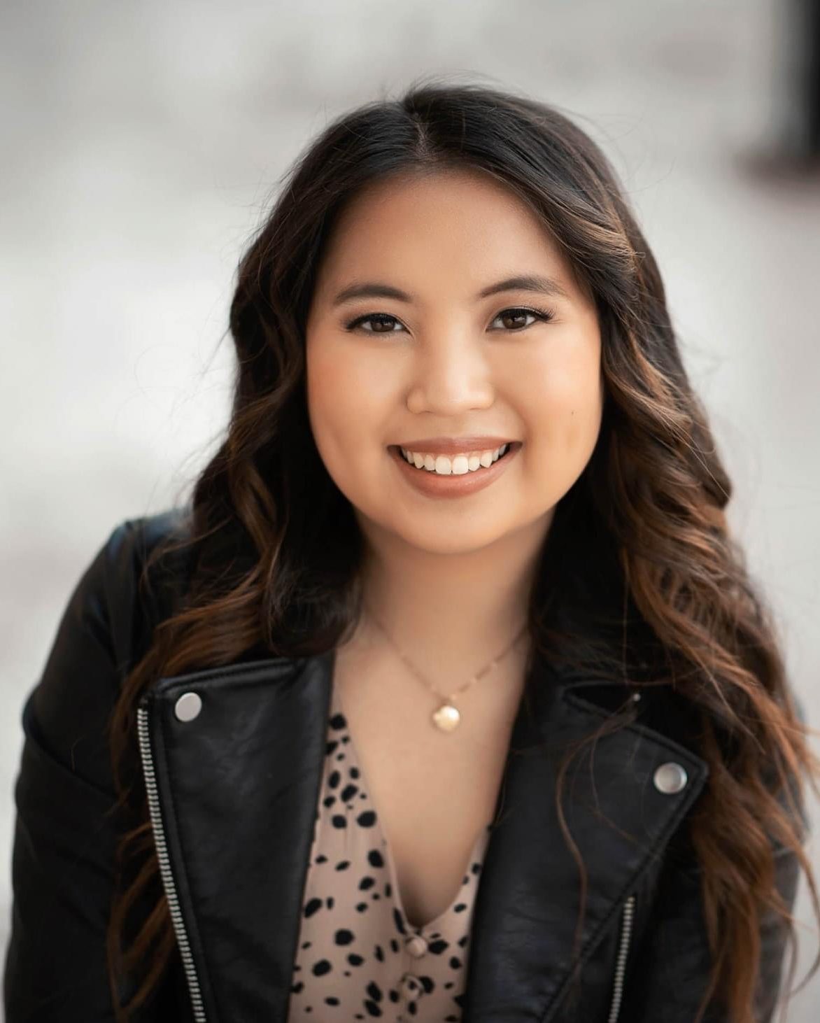 smiling girl with brown curly hair wearing leather jacket