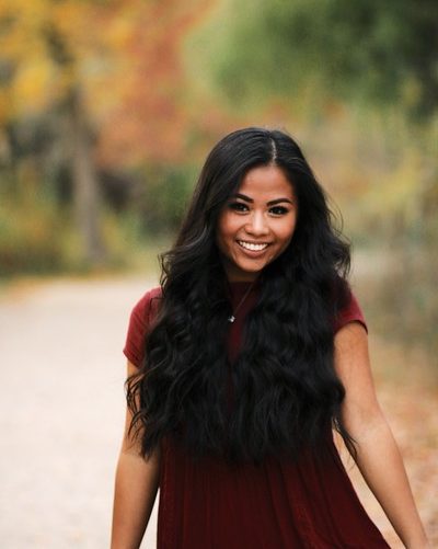 smiling girl with long wavy hair wearing red dress