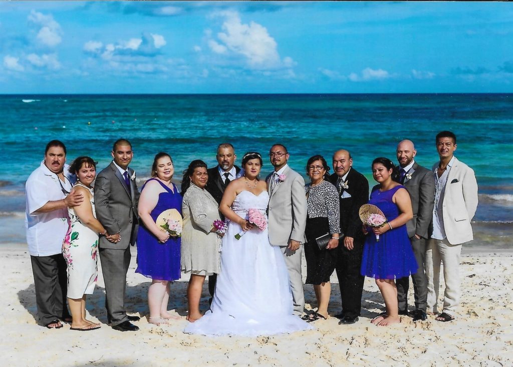 group of people in wedding clothes standing on a beach