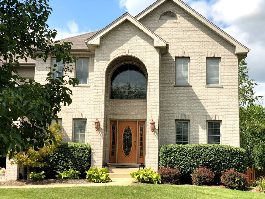 two story white brick house with brown door