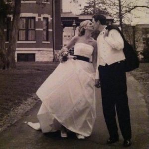 black and white photo of woman in wedding dress kissing man in suit