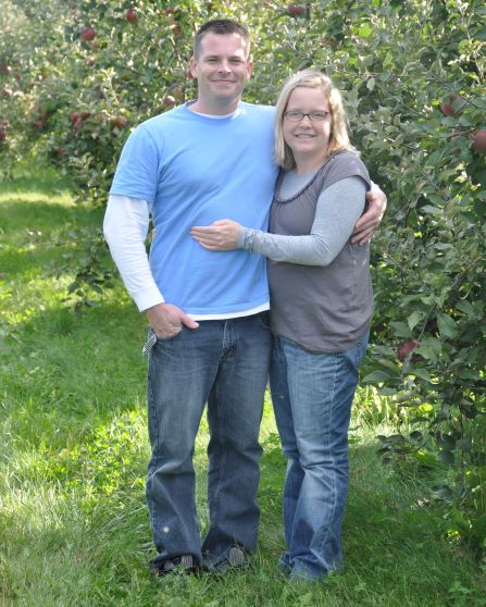 smiling woman with arm around smiling man in apple grove
