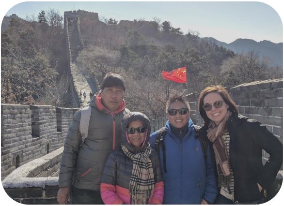four people smiling for a picture at the great wall of china