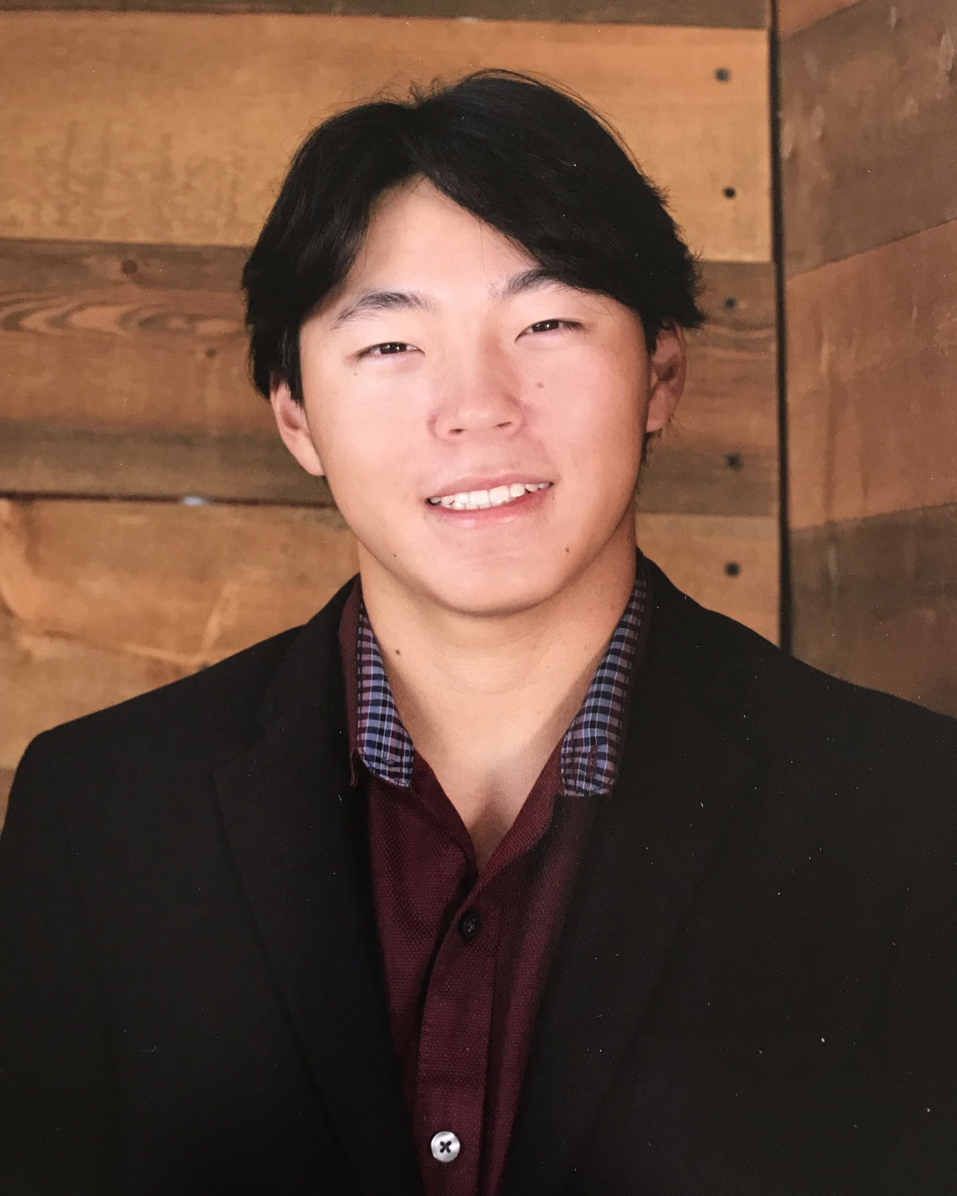 smiling man wearing red shirt and black blazer