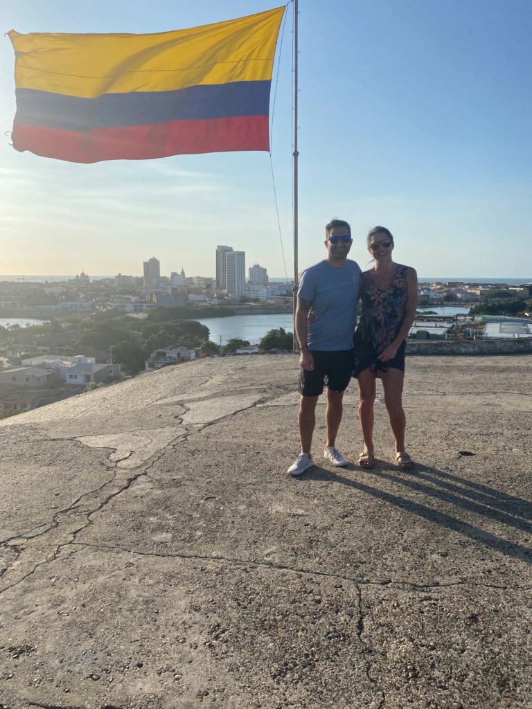 man and woman standing in front of flag with yellow blue and red stripe