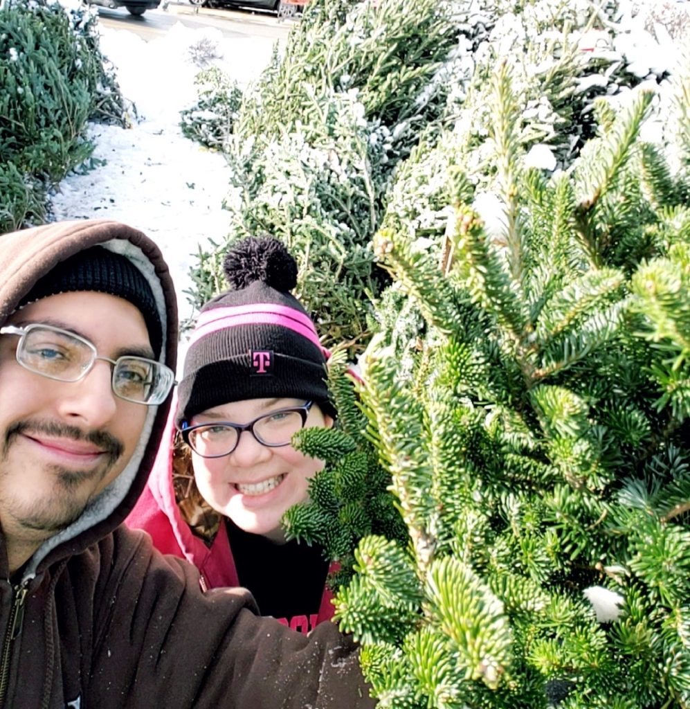 selfie of smiling man and woman with christmas tree at farm