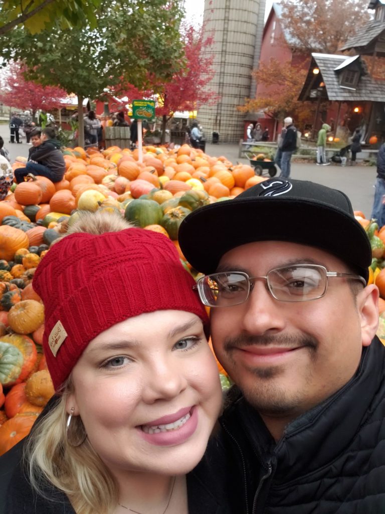 smiling man and woman in front of pumpkin display