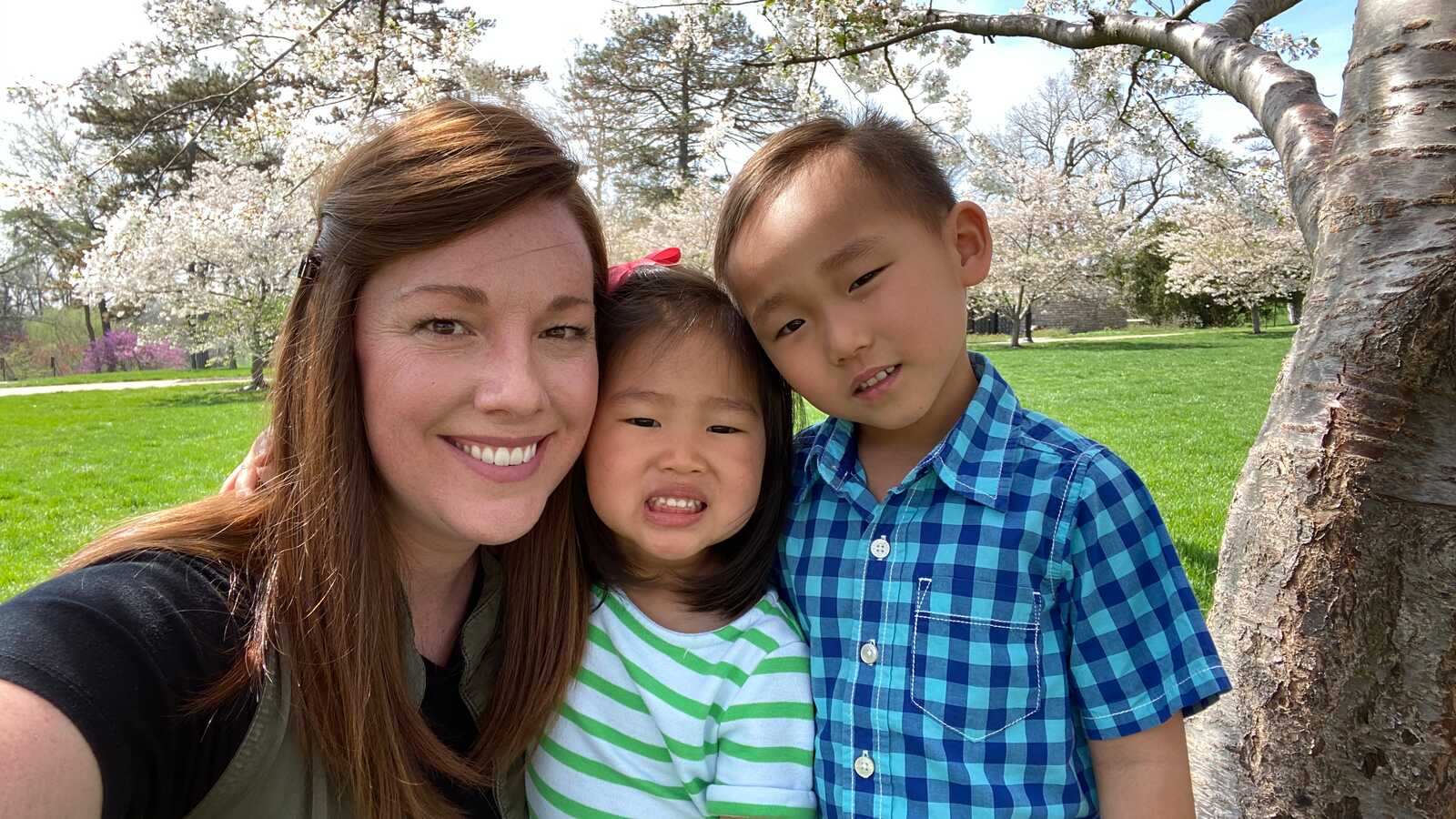 woman smiles for camera with two adopted children