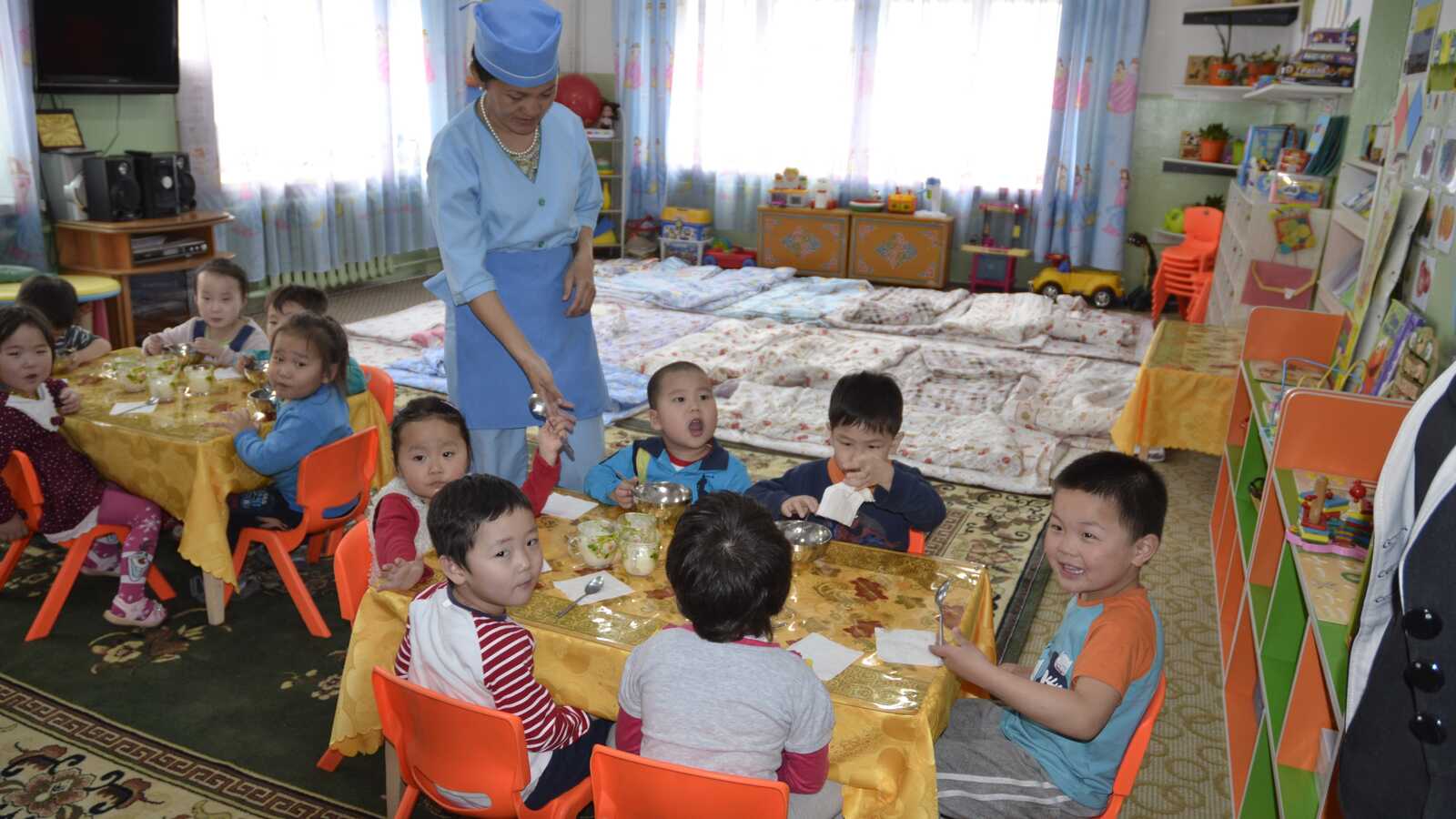woman carrying for children during lunch in Mongolian orphanage